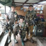 three boys posing with ducks