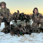 Two young hunters with ducks in winter