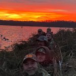 Hunters by a lake at sunset