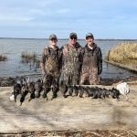 3 hunters with row of hunted ducks