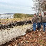 3 men and row of hunted ducks on a log